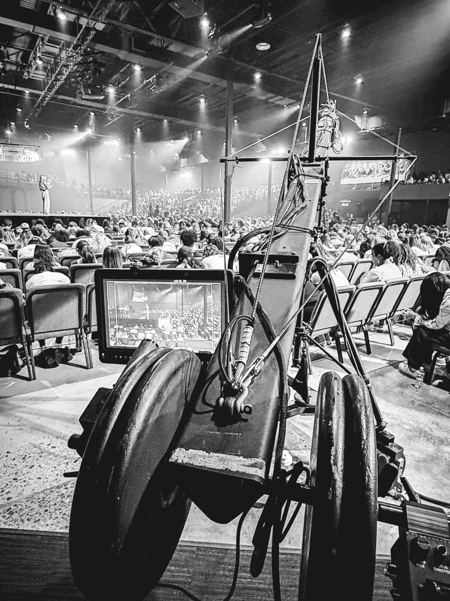Camera jib extending over an audience toward a live-event stage